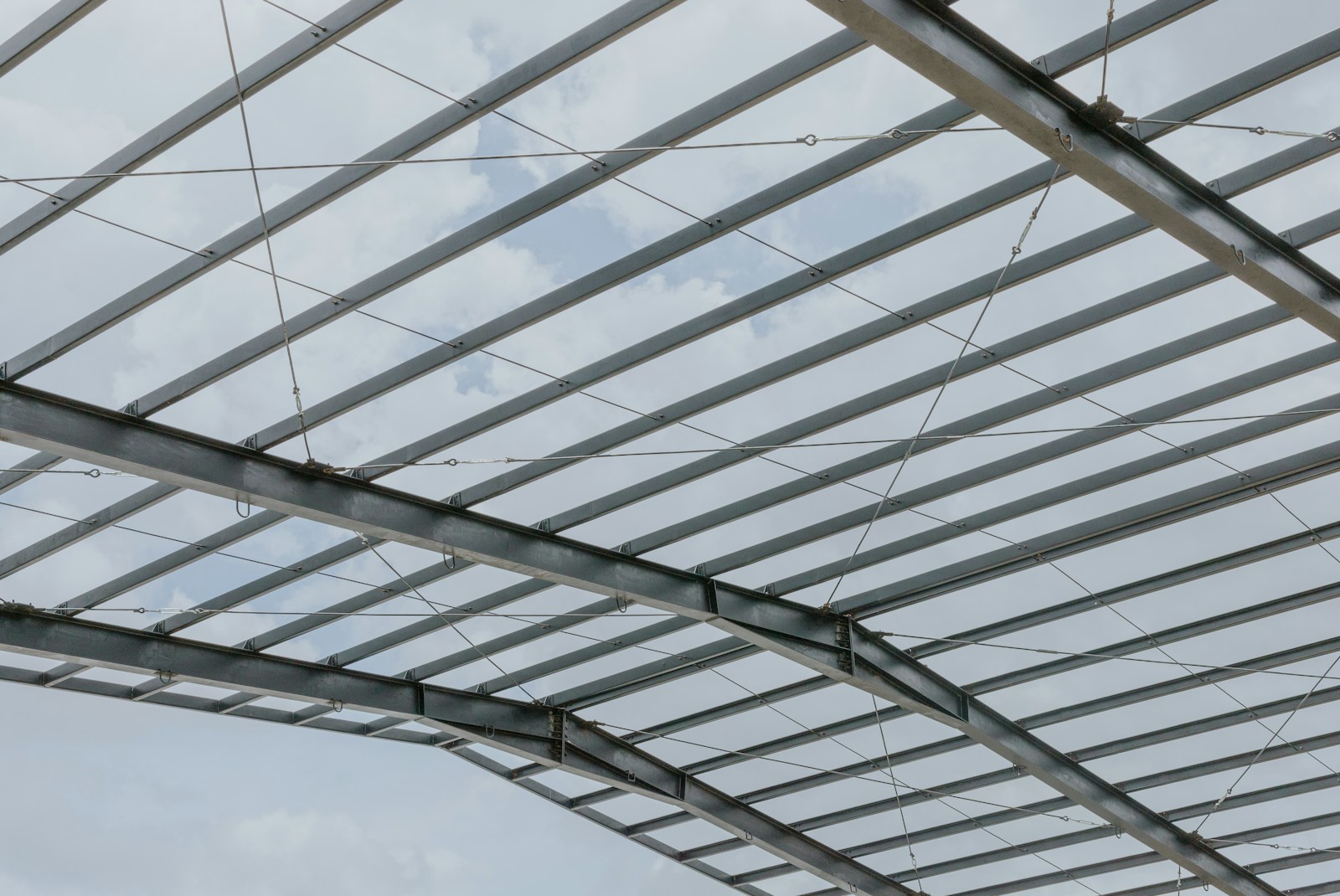 Steel framework with layered beams against a pale sky
